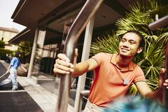 Smiling bellhop pushing a luggage trolley outside a hotel entrance.