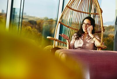 woman on phone in hanging egg chair