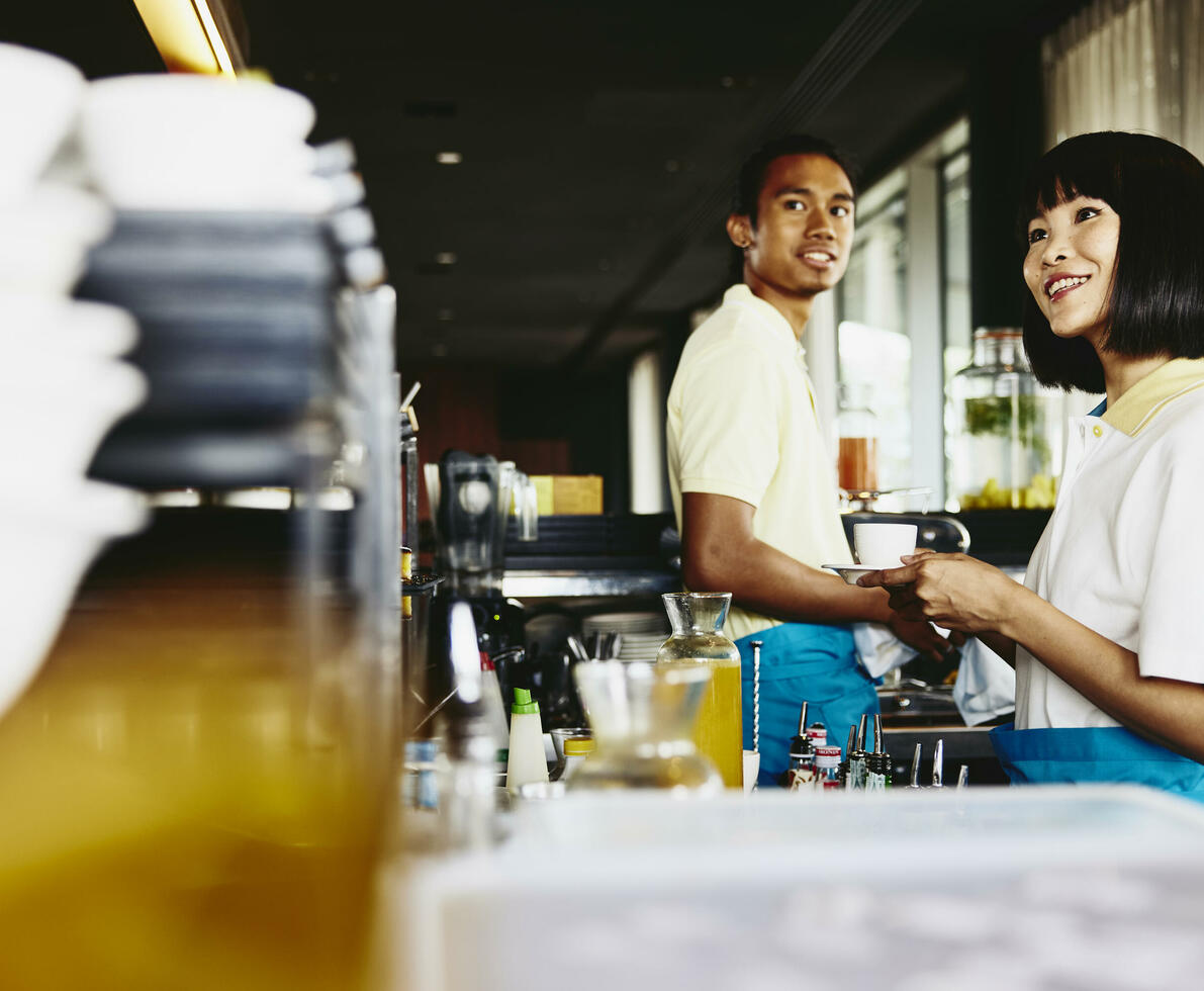 male and female bar tending. Womale holding acoffee cup.
