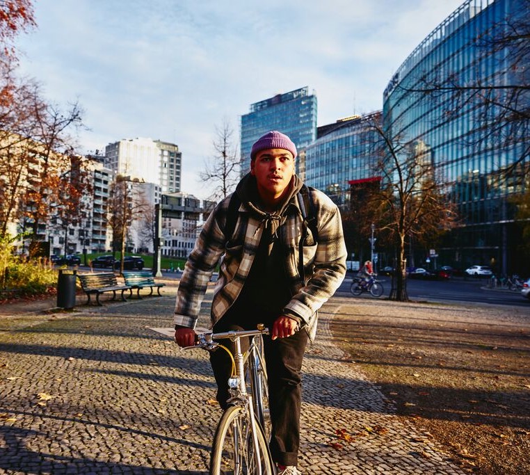 Cycling man, autumn trees and office buildings on the background.