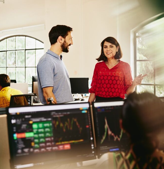 Two colleagues man and woman having a chat standing between desks.