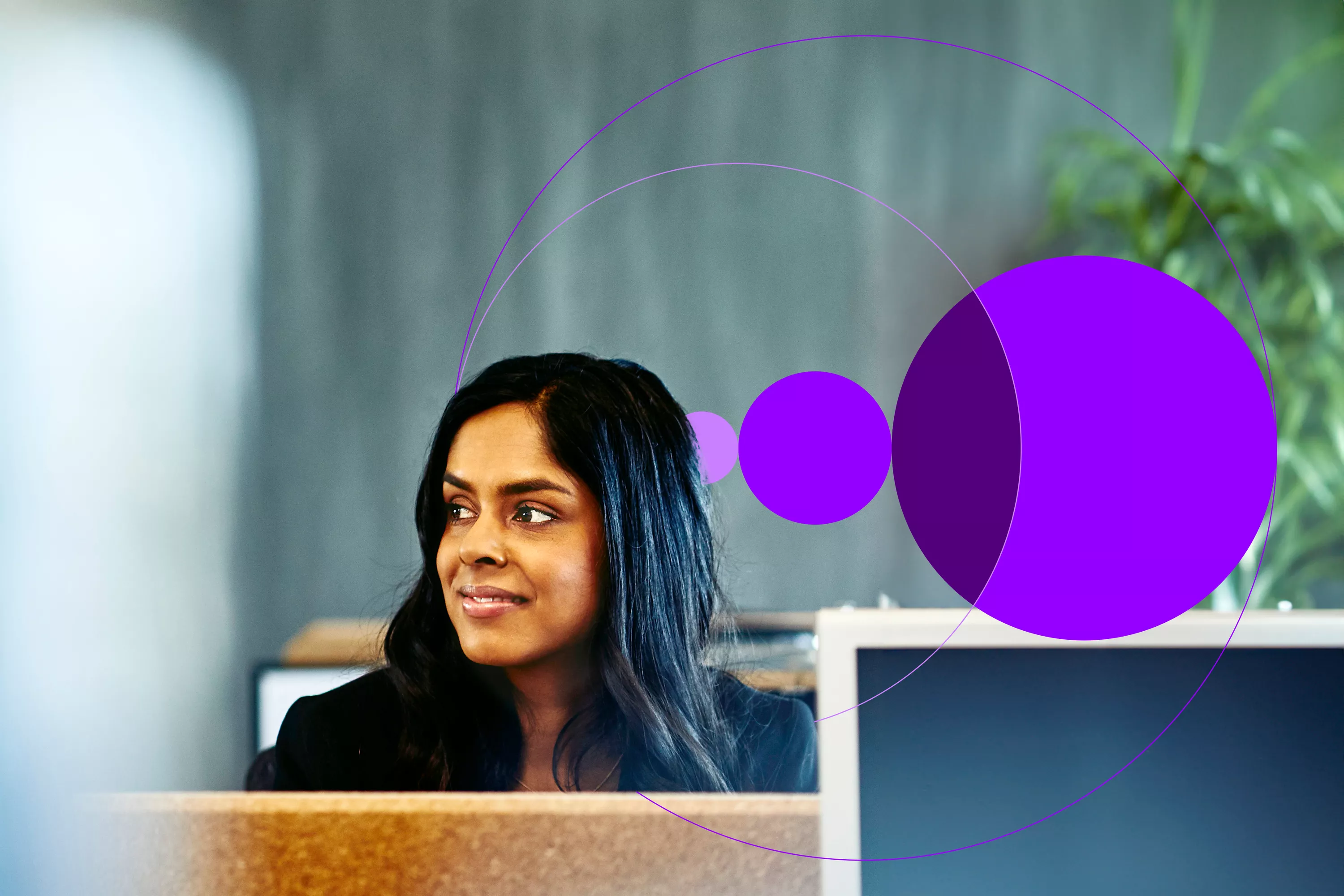 Woman at her desk, behind her computer.